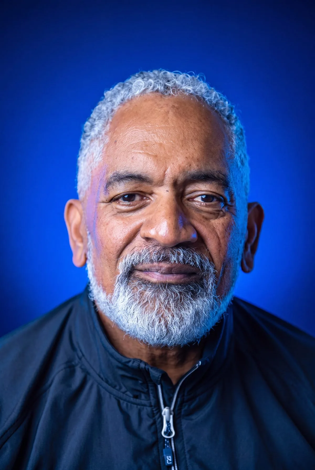 Chris Scott, close up, lit against a deep blue field.
